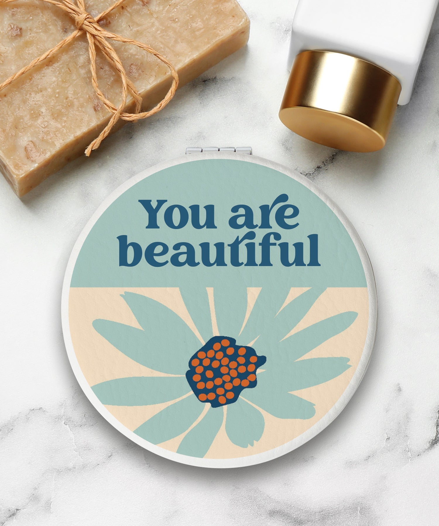 Round compact mirror with a leatherette cover, full-color “You Are Beautiful” design, 1X and 2X mirrors inside, and magnetic closure.