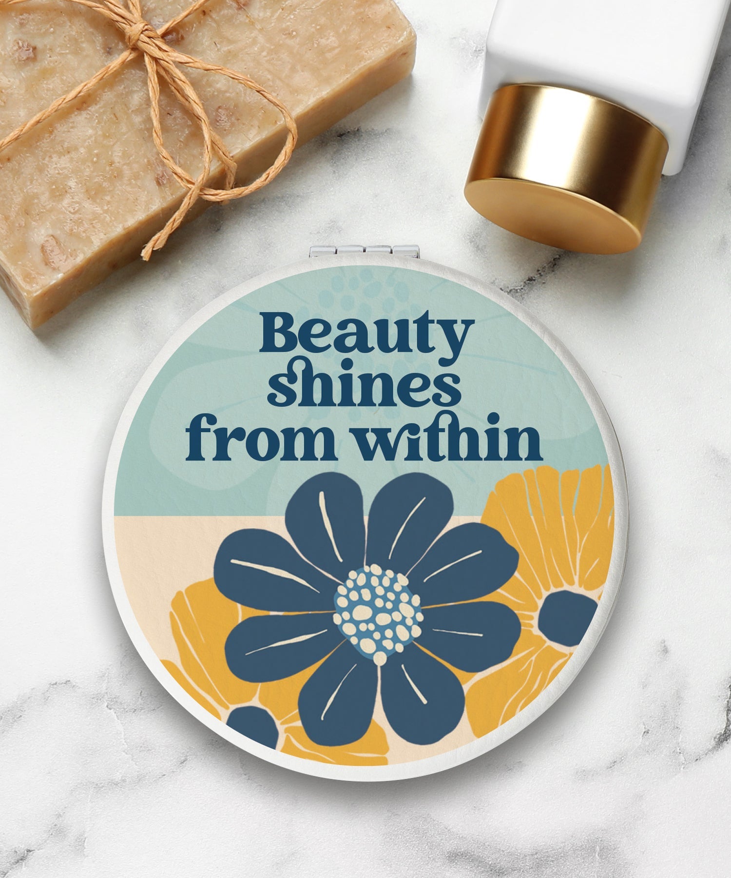 Round compact mirror with a leatherette cover, full-color “Beauty Shines From Within” design, 1X and 2X mirrors inside, and magnetic closure.