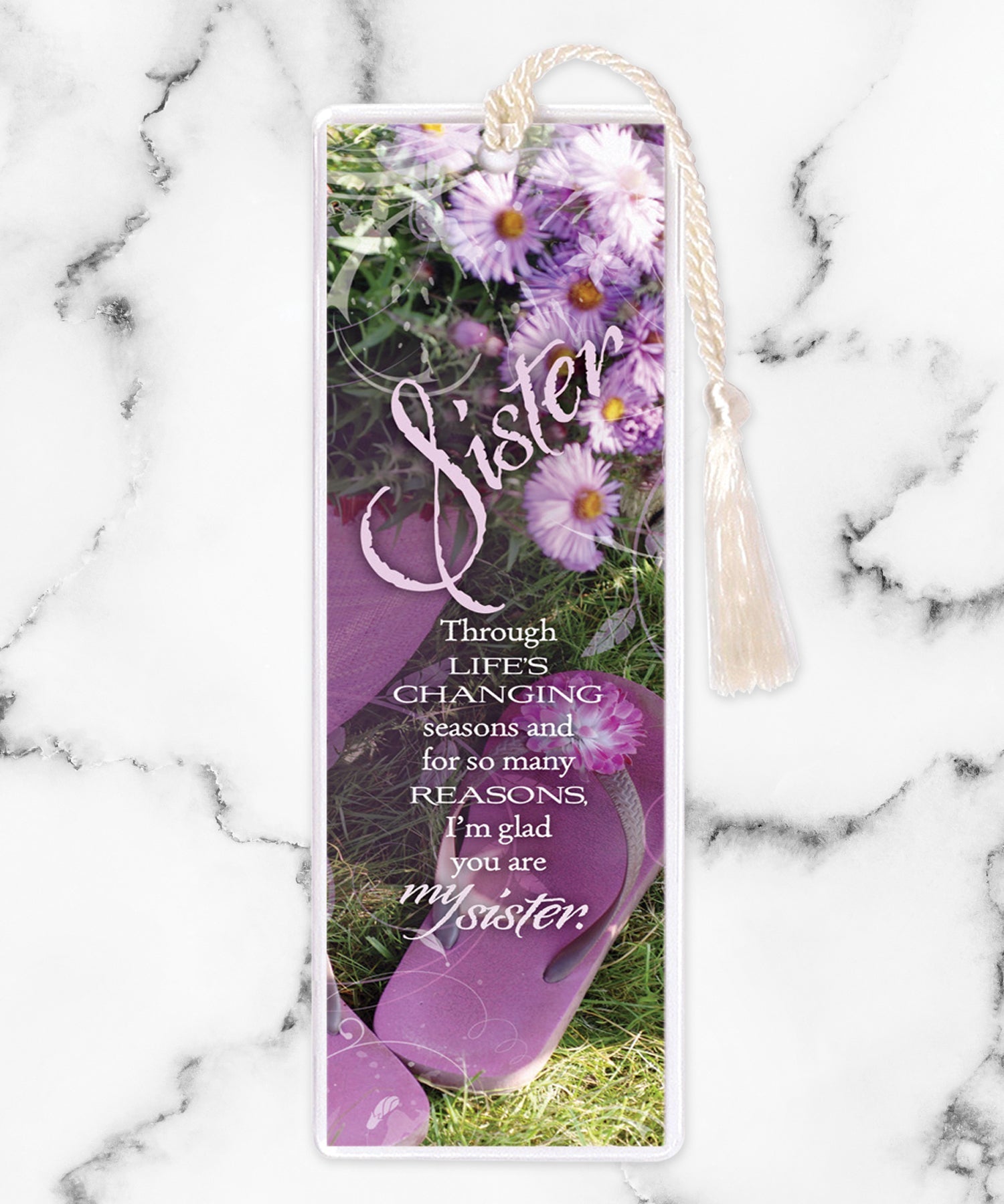 An elegant double-sided bookmark, Sister, is protected by a clear vinyl sleeve and finished with a tassel.