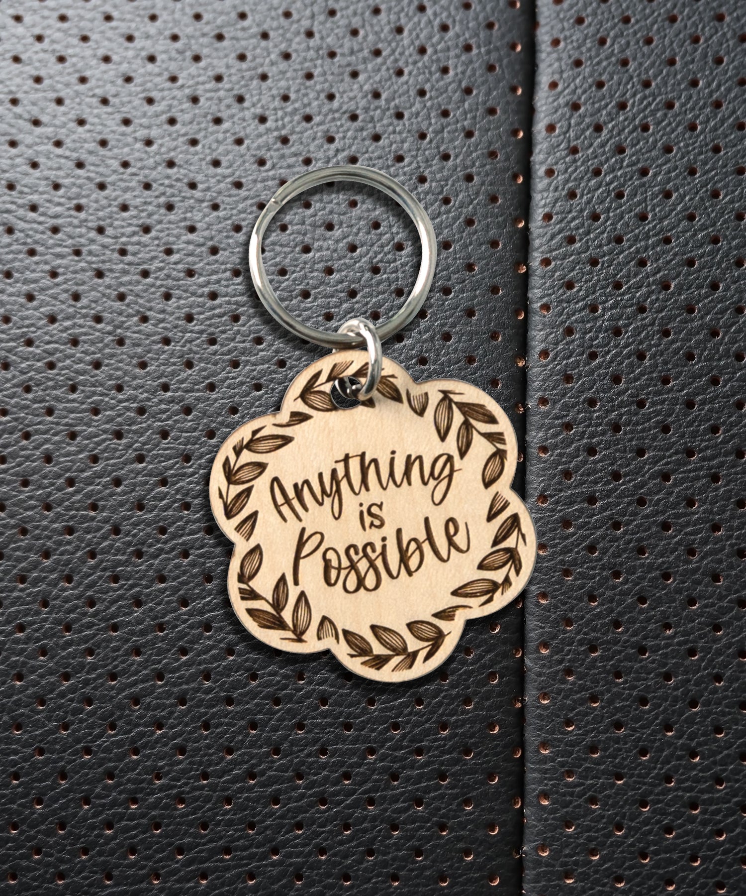 Natural maple wood keychains have a laser-cut shape and laser-engraved Anything is Possible inspirational verse.