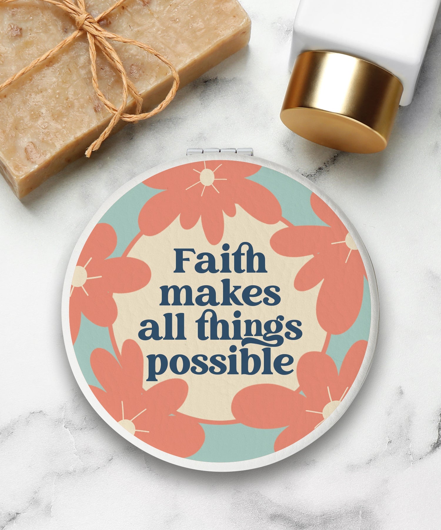 Round compact mirror with a leatherette cover, full-color “Faith Makes All Things Possible” design, 1X and 2X mirrors inside, and magnetic closure.