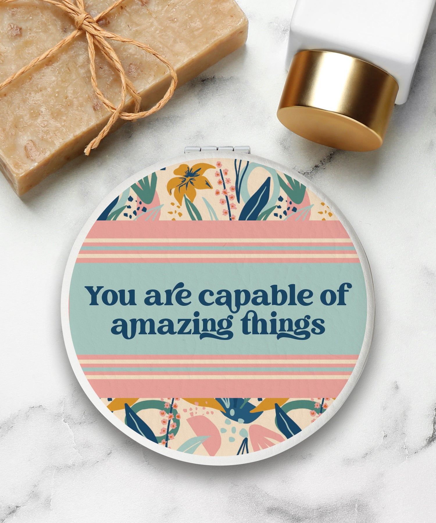 Round compact mirror with a leatherette cover, full-color “You Are Capable” design, 1X and 2X mirrors inside, and magnetic closure.