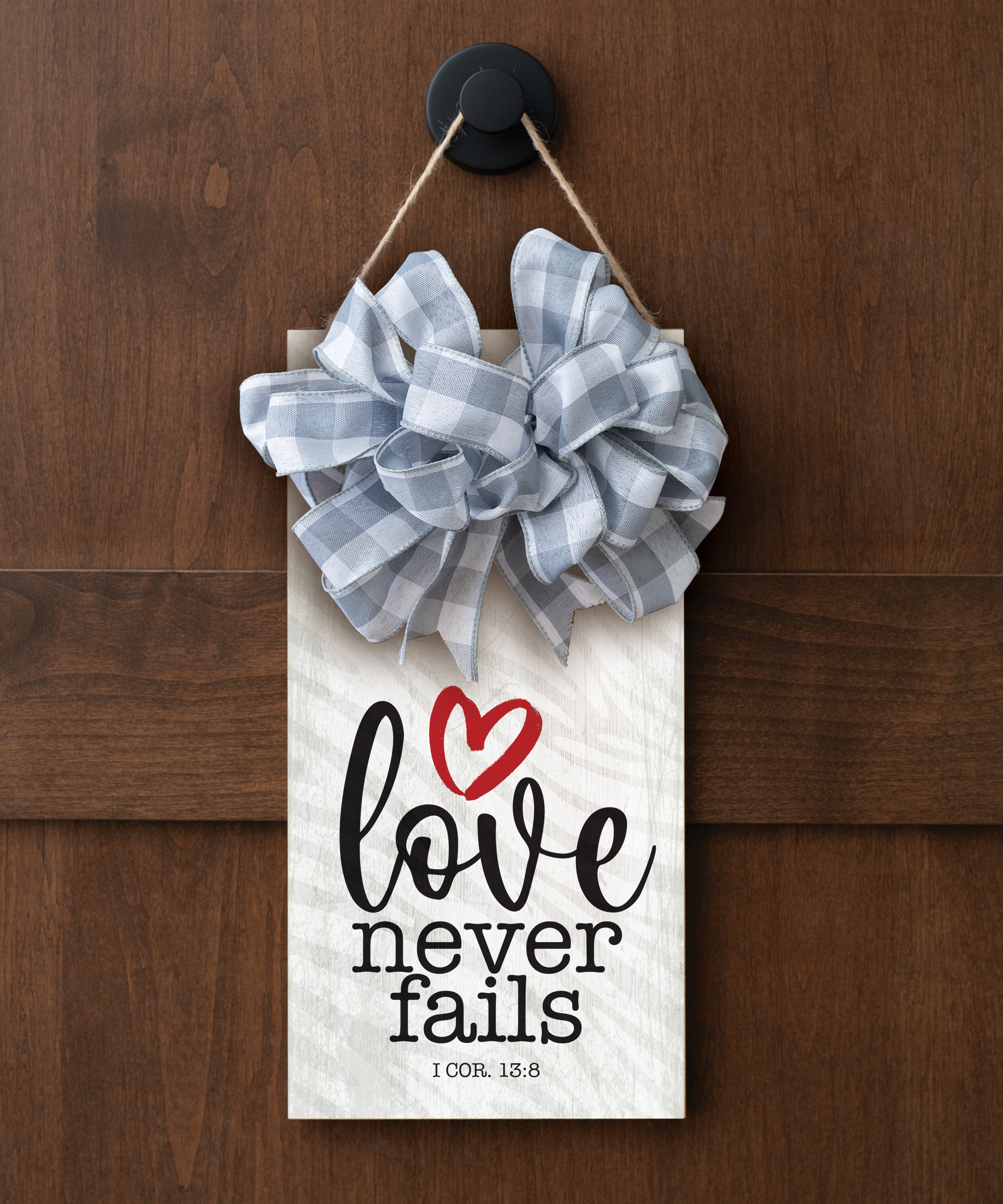 Love Never Fails hangable blessing with jute twine cord, fabric bow, and full-color printed verse