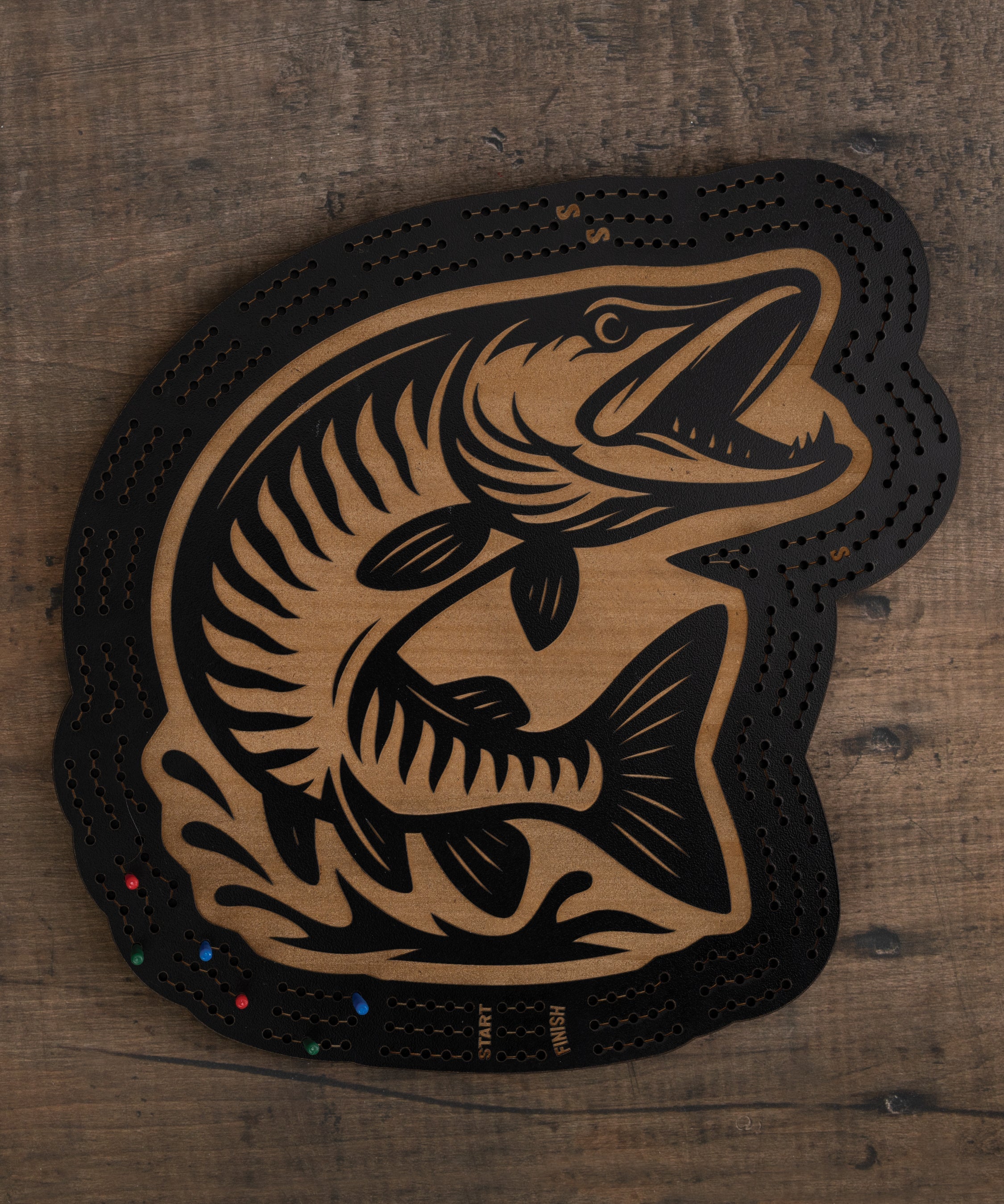 Muskie cribbage board with black and brown fish artwork and built-in peg storage