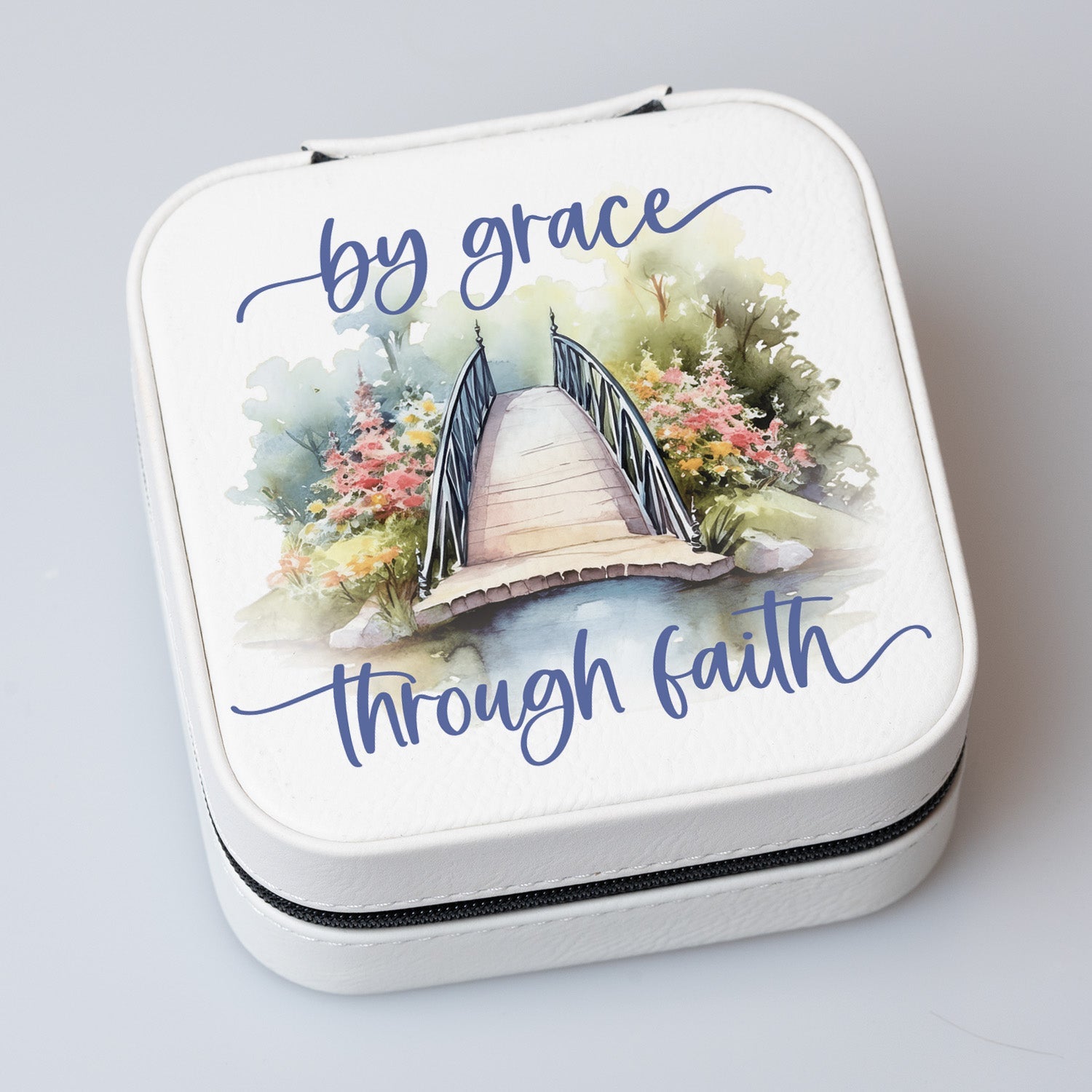 By Grace Travel Jewelry Case in off-white leatherette with a zipper closure and plush black velvet interior.